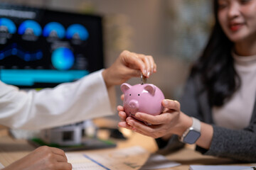 Businesswoman putting coin in piggy bank for savings and investment with financial advisor