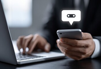 Businessperson using laptop and phone, message icon