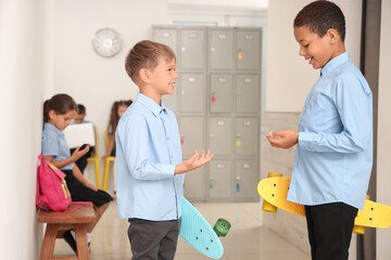 Little boys with skateboards talking at school hall