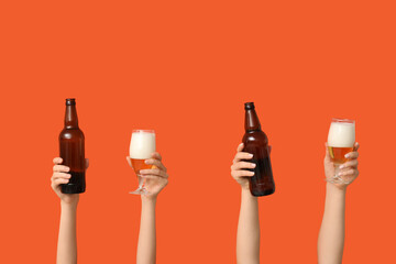 Female hands with bottles and glasses of fresh beer on orange background