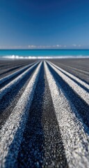 Parallel tire tracks on dark beach lead to ocean