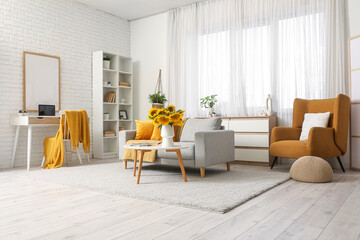 Interior of living room with sofa, workplace and sunflowers on coffee table