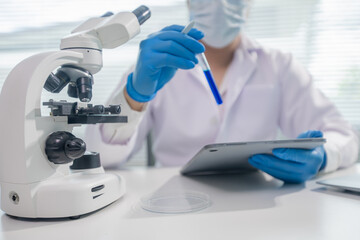 Fototapeta premium Scientist in laboratory conducting medical and biochemistry research, examining liquids in test tubes with advanced technology and microscope for healthcare, pharmaceutical development, and genetic in