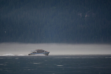 Fototapeta premium Tourists head out of Seward, Alaska, on a foggy morning for a day of sightseeing and wildlife watching in Resurrection Bay.