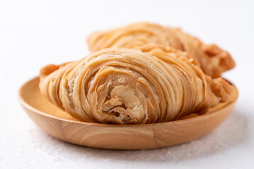 Curry puff stuffed with chicken or sweet potatoes on wooden plate with white background, Thai snack food style