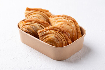 Curry puff stuffed with chicken or sweet potatoes in paper food box on white background