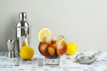 Glass of Long Island iced tea cocktail on grey tile background