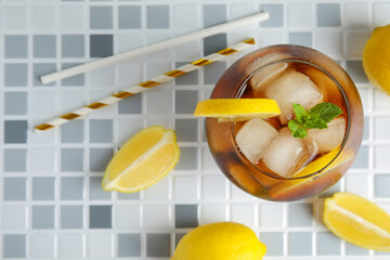 Glass of Long Island iced tea cocktail with mint on grey tile background