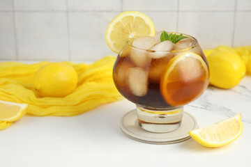 Glass of Long Island iced tea cocktail with mint on white table