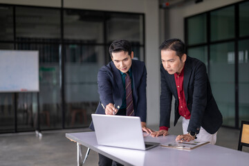 Two businessmen working together using laptop in office meeting room