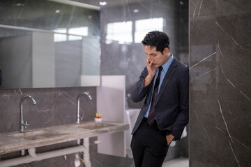 Stressed businessman suffering headache in office restroom