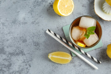 Glass of Long Island iced tea cocktail with mint on grey background