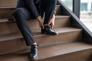 Businessman suffering from ankle pain while sitting on stairs