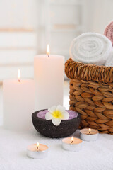 Burning candles, bowl of sea salt and clean towels on massage table