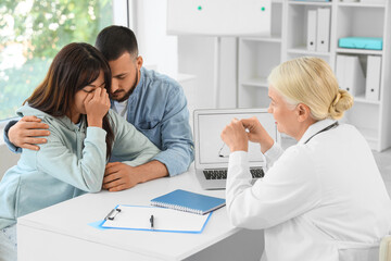 Obraz premium Upset young couple visiting fertility doctor about IVF at table in clinic