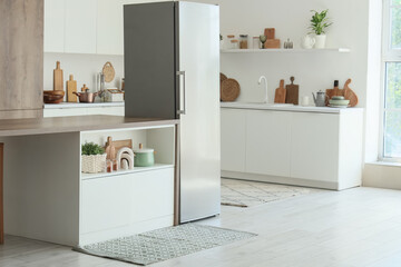 Interior of modern kitchen with big fridge, table and counters