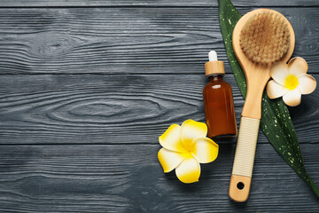 Beautiful spa composition with massage body brush, bottle of cosmetic product and plumeria flowers...