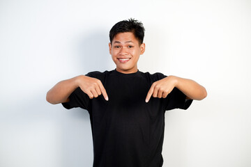 A smiling young Asian man wearing a black shirt points down © Ichsan Gallery
