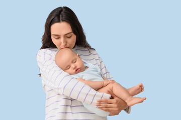 Happy mother kissing her little baby on light background. IVF concept