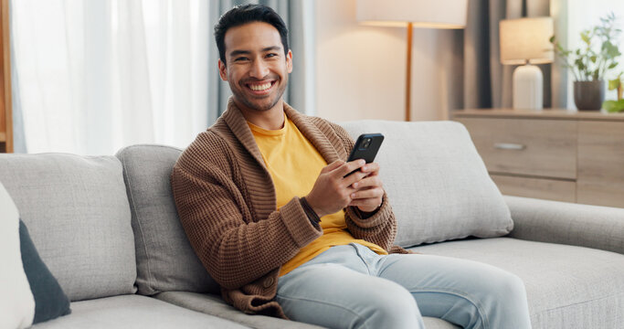 Phone, portrait and smile with man on sofa in living room of home for social media scrolling. App, browsing and communication with happy person typing in apartment for internet search or text message - Powered by Adobe
