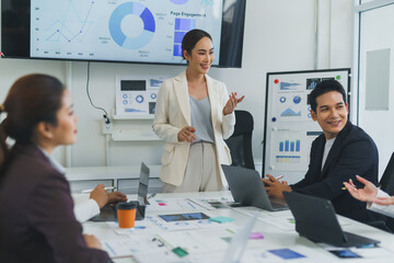 Asian businesswoman leading a meeting with diverse colleagues, presenting financial charts and...