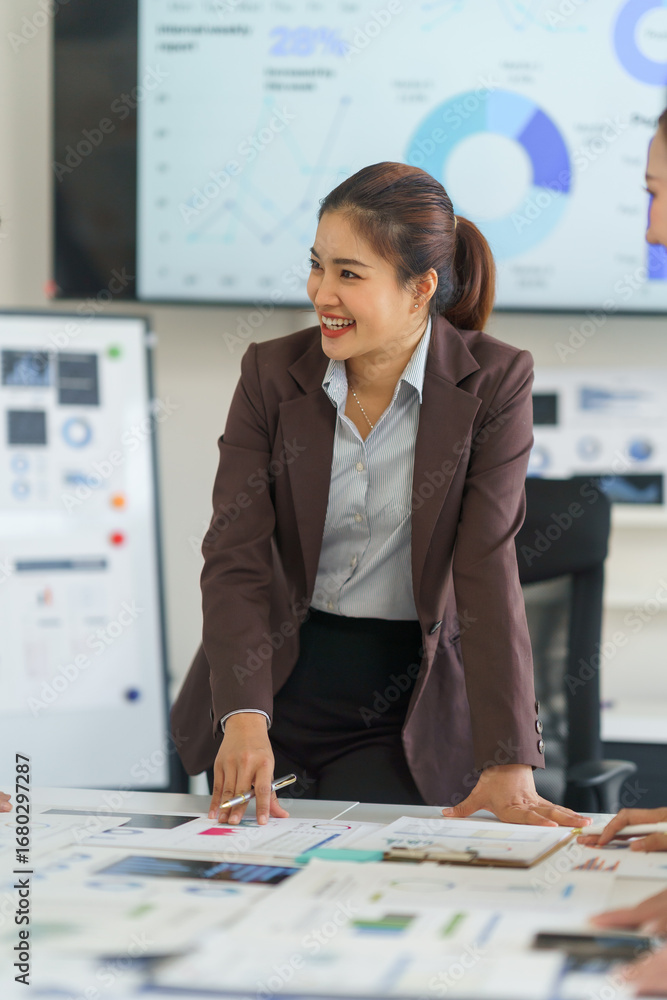 Poster asian businesswoman smiling while explaining charts and graphs during a collaborative meeting with c