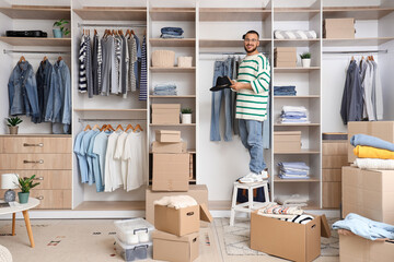 Young man with hat on stool and boxes in wardrobe