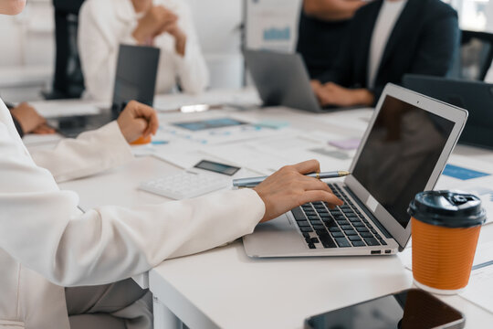 Businesswoman collaborating with colleagues while using a laptop during a meeting, actively working together on a project in a modern office setting