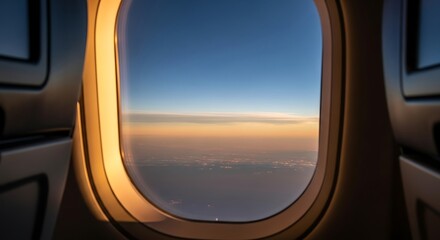Photo of view from an airplane window shows a vast sky at sunset with clouds and city lights below