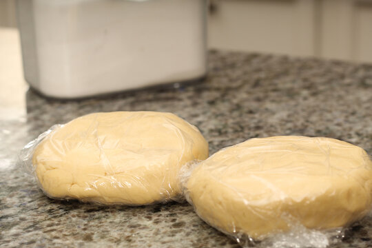 Two Pads of Cookie Dough Wrapped in Cling Film on Countertop
