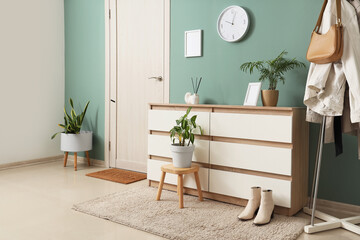 Interior of hallway with wall clock, commode and clothes rack
