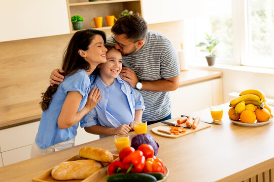 Family cooking together in a bright kitchen filled with fresh produce