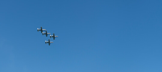 Four fighter jet in V shape in sky. Squadron. Air Force Day. Aircraft squadron on a mission. US air force. Military air force fighter jet airplane in full flight against blue sky. Air force jet