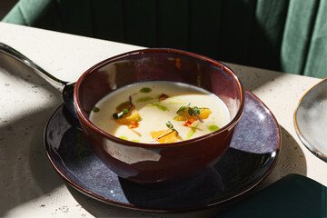 Broccoli cream soup with green oil and orange, bright sunlight, closeup composition