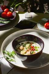 Salmon creamy soup in rustic bright lighting, overhead composition with herbs and vegetables