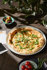 Four cheese pizza with arugula in bright natural lighting, overhead composition