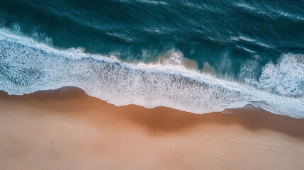 Crashing waves meet golden sands in a tranquil aerial view of the ocean's edge