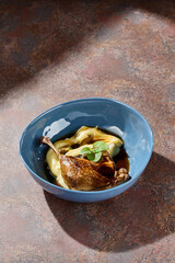 Duck leg with celeriac puree in blue bowl, bright natural lighting, overhead restaurant composition