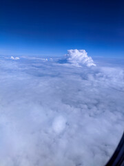 Obraz premium Expansive view above the clouds with a bright blue sky and towering cumulus formation, showcasing the beauty of aerial landscapes, peaceful atmosphere, and high-altitude travel scenery.