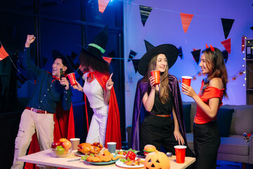 Joyful office Halloween party with coworkers in costumes, celebrating with drinks and laughter, fostering teamwork