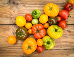 A vibrant assortment of colorful tomatoes displayed on a rustic wooden surface.