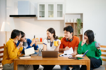 Young Asian adults collaborating on laptops and tablets in a cozy workspace, embodying teamwork, c