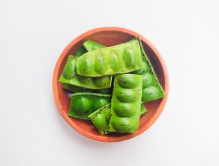 Raw Petai (Parkia Speciosa) or Bitter Bean in a wooden plate on a white background.