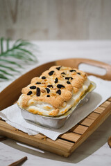 Manado's signature klapertart topped with almonds and raisins, served in individual containers. A rich and delicious creamy coconut dessert