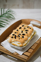 Manado's signature klapertart topped with almonds and raisins, served in individual containers. A rich and delicious creamy coconut dessert