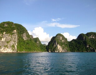 Lush green islands rise from calm blue waters under a partly cloudy sky