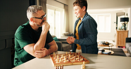 Excited, chess and father with boy, home and family with competition, proud and winner. Apartment, parent and dad with happy son, game and victory with cognitive development, challenge and checkmate
