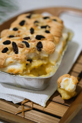 Manado's signature klapertart topped with almonds and raisins, served in individual containers. A rich and delicious creamy coconut dessert