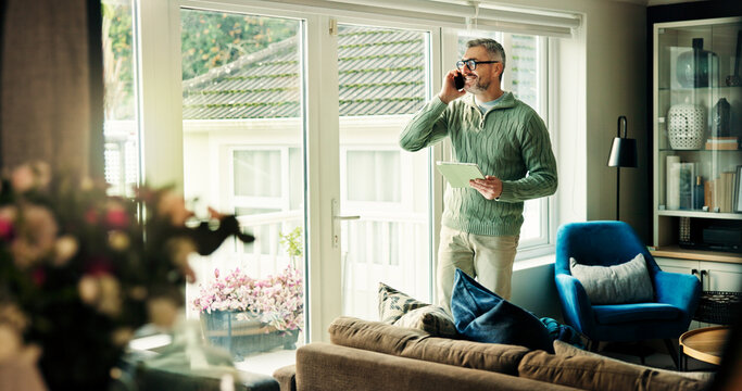 Remote work, phone call and happy man with tablet in home for listening, chat or insurance policy. Freelancer, mobile and mature broker talking to contact for negotiation, claims update or news - Powered by Adobe