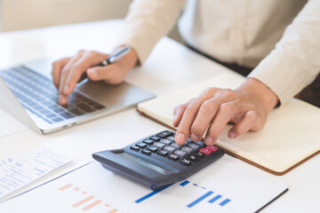 Fototapeta premium Account finance, asian young business man hand using calculator, laptop computer for calculate budget, cost and income of company from paperwork, plan spend money expenses, working on desk at home.